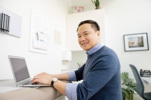 Man smiling at the camera while doing admin work